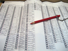 Een stembiljet met daarop een rood potlood aan een ketting